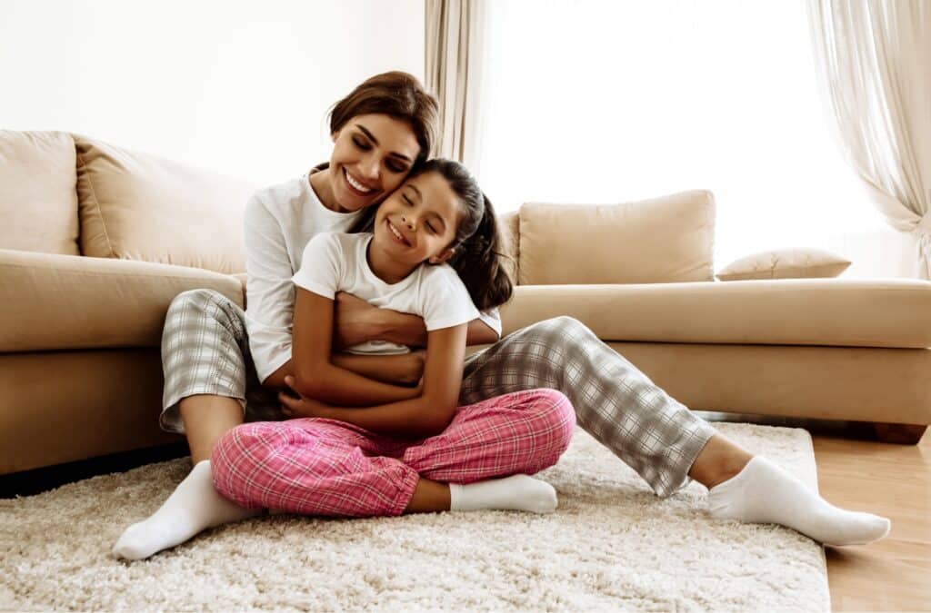 mother hugging her daughter on living room floor