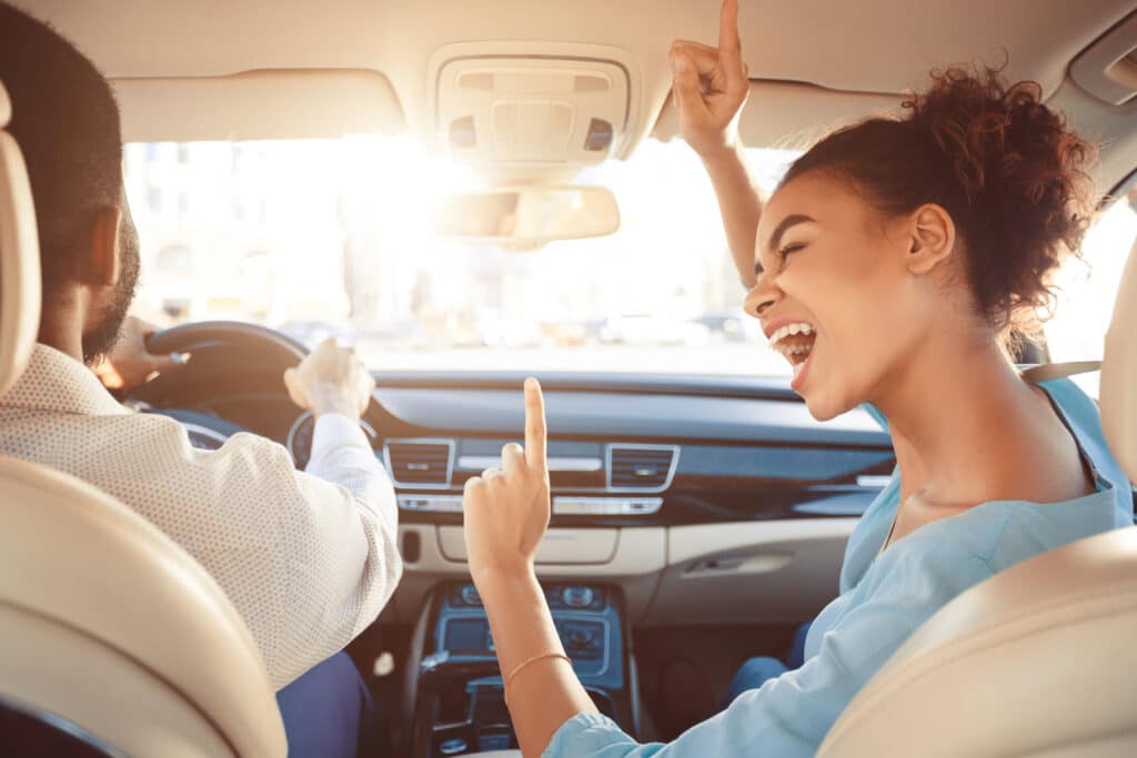 couple driving and singing out in car