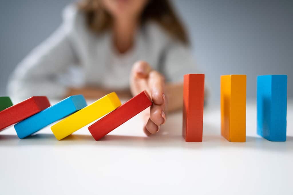 woman stopping colorful dominos from falling over