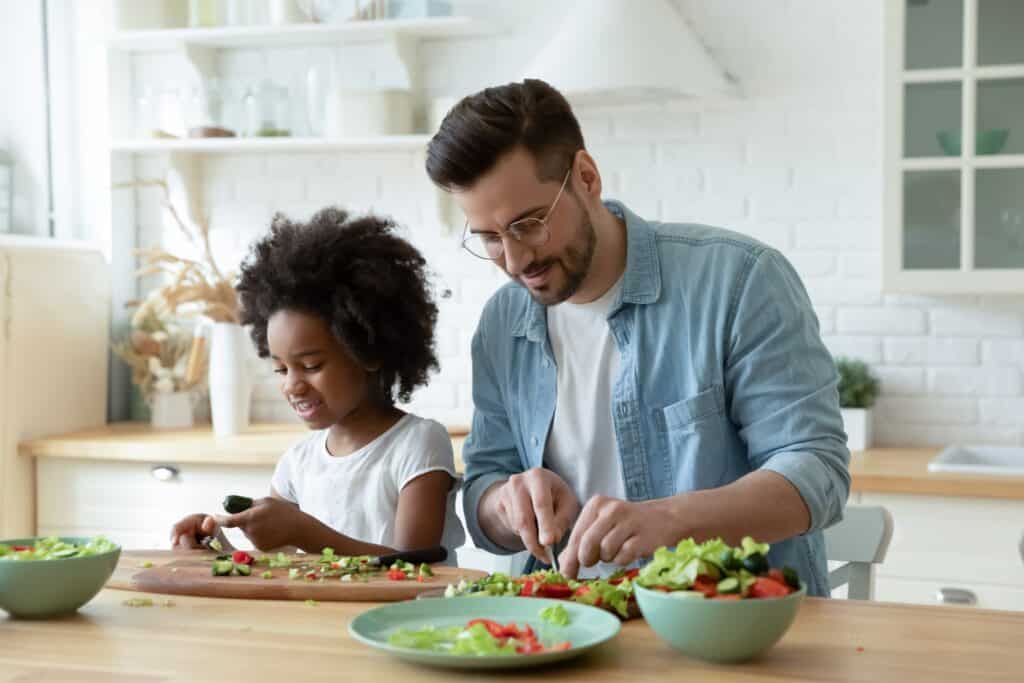 father preparing salad with his daughter