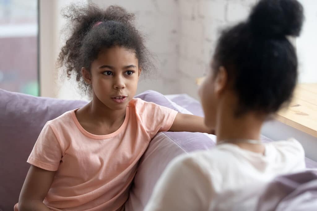 young girl talking to her mother on couch