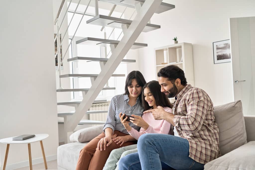 parents sitting on a couch with their teen daughter looking at cell phone