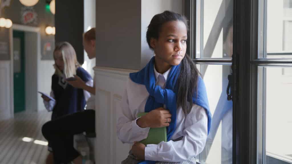 sad teen looking out school window