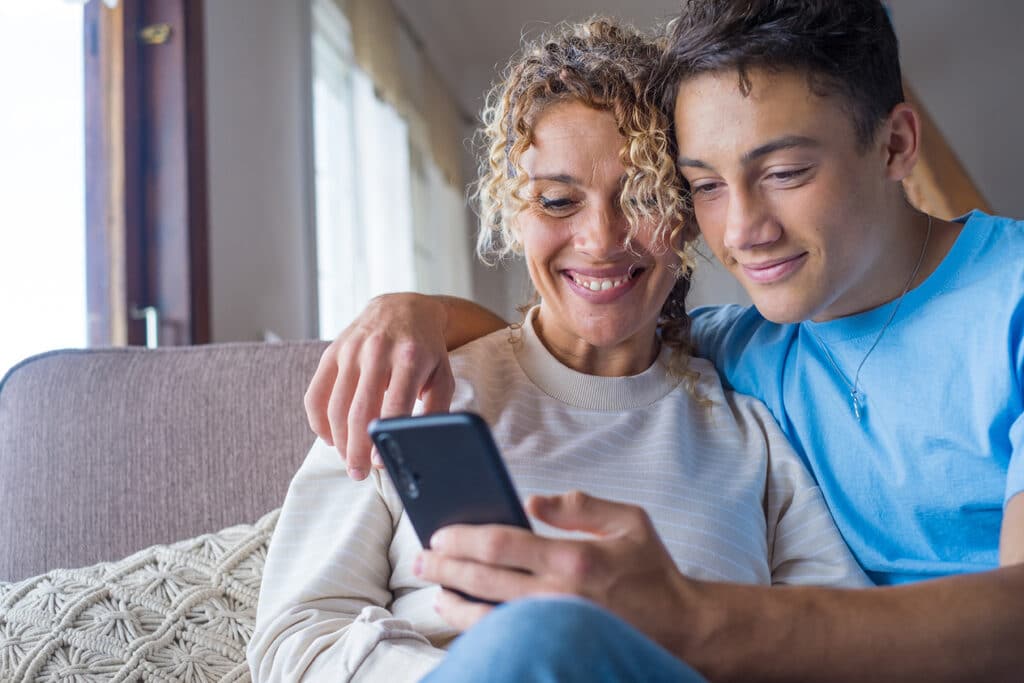 mother and teenage son smiling looking at a phone