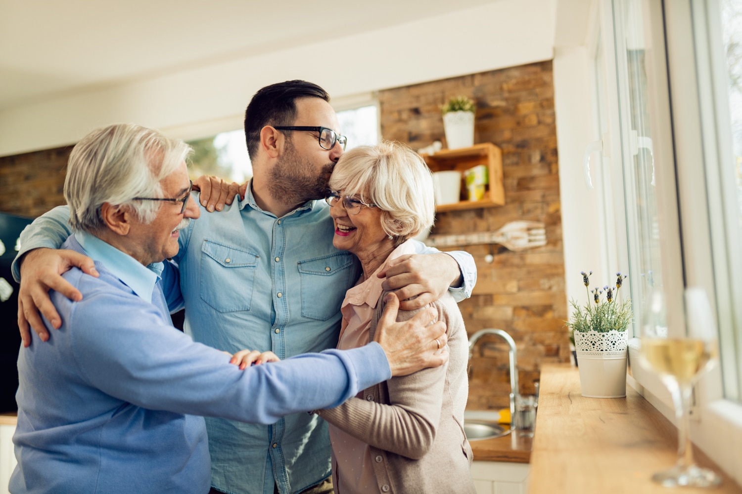 son hugging and kissing elderly parents