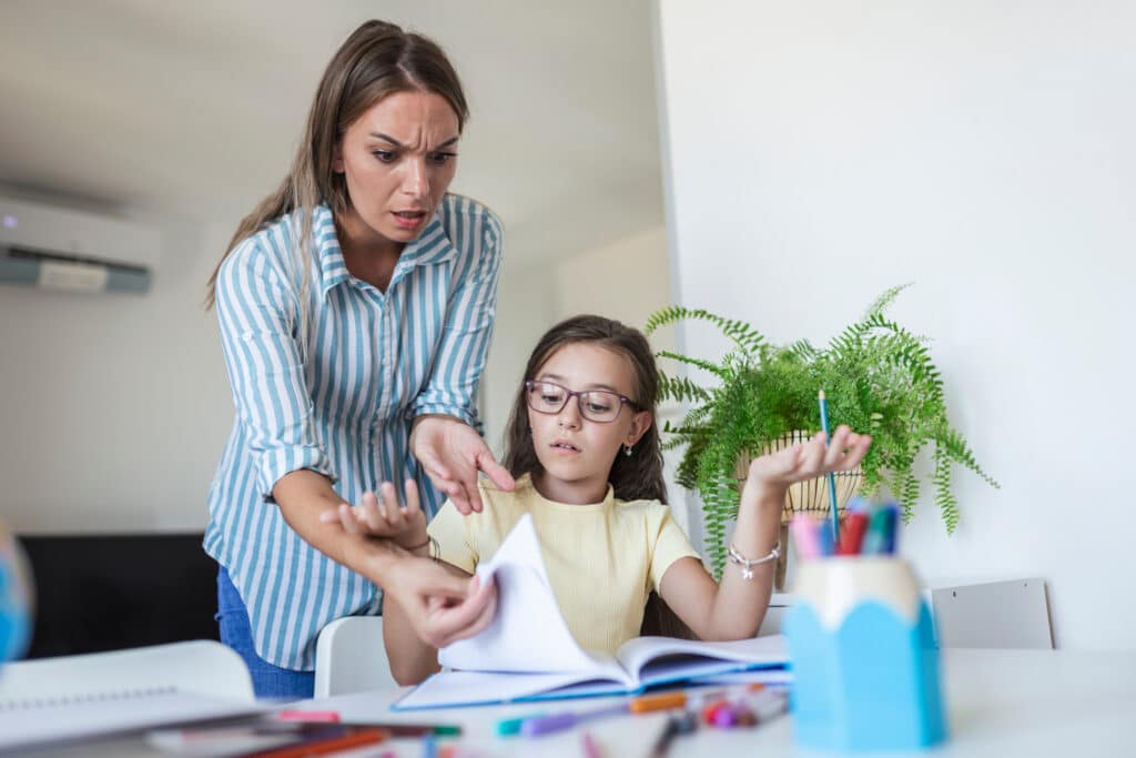 upset mother looking at surprised daughter working on homework