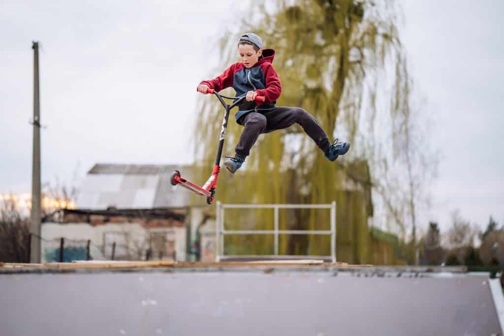 Boy doing scooter trick in skate park