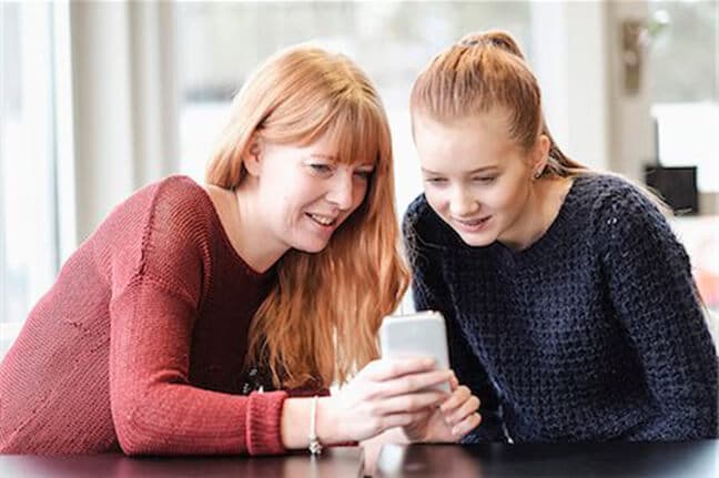 Mother showing her daughter how to use her first phone