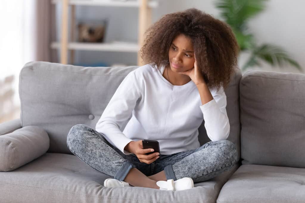 teen girl looking at cell phone distraught