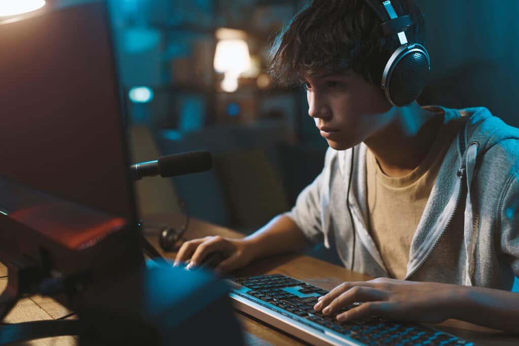 teenage boy playing video games at his computer