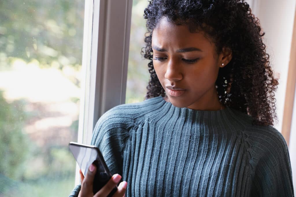 young woman looking at her phone concerned