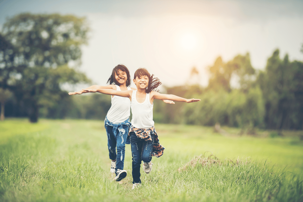 two little girls frolicking in grassy field