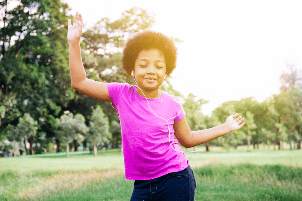 young girl listening to earbuds and dancing happily